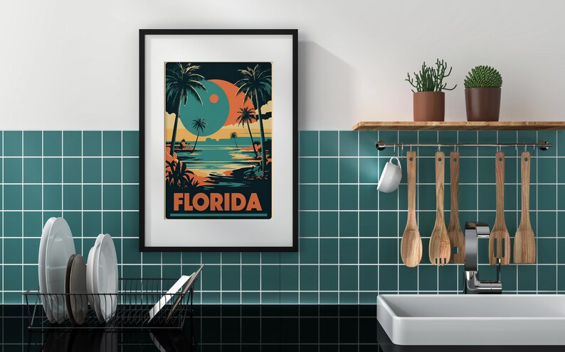 Peut inclure: Une affiche encadr&eacute;e avec un design r&eacute;tro repr&eacute;sentant une sc&egrave;ne de plage avec des palmiers et un grand orbe orange et bleu dans le ciel. L'affiche indique "FLORIDA" en lettres orange et grasses.