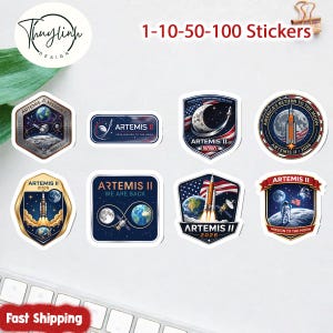 以下が含まれることがあります： さまざまなデザインのアルテミスIIミッションステッカーのコレクション。ステッカーには、ロケット、月、地球、アメリカ国旗が描かれています。「Artemis II」、「NASA」、「America's Return to the Moon」などのテキストが含まれています。
