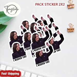 May include: A pack of 2x2 stickers featuring a smiling woman in a dark purple suit waving. The stickers have the text "I WARNED YOU!" printed on them. The stickers are arranged on a white surface.