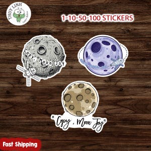 Pode incluir: Uma coleção de autocolantes com corpos celestes. Os autocolantes incluem uma lua cinzenta com uma nave espacial, um planeta roxo com uma nave espacial e uma lua castanha. O texto "Copy. Moon Joy" está nos autocolantes. O texto "1-10-50-100 STICKERS" também está presente.