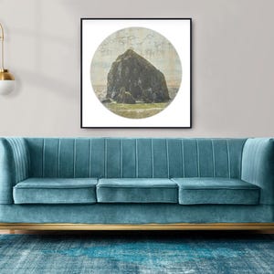 May include: A teal velvet sofa with gold trim and a framed print of a large rock formation in a circular frame. The sofa sits on a blue patterned rug, with a gold floor lamp and a tall green plant in the background.