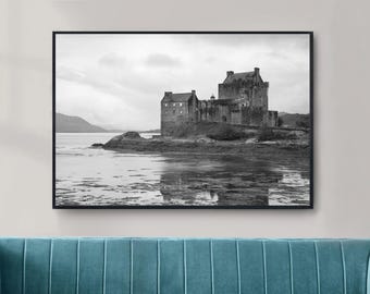 May include: Black and white framed print of a castle on a rocky island. The castle has multiple towers and is reflected in the water. The sky is overcast, and the overall scene is serene.