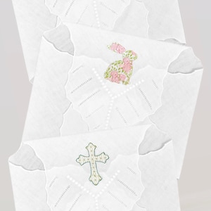 May include: Three white embroidered handkerchiefs with different designs. The top handkerchief features a green bunny in a blue and white planter. The middle handkerchief features a pink bunny with floral accents. The bottom handkerchief features a silver cross with rhinestones.