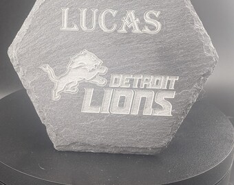 May include: A gray hexagonal slate coaster with the Detroit Lions logo and the text "Lucas" and "DETROIT LIONS" engraved on it.
