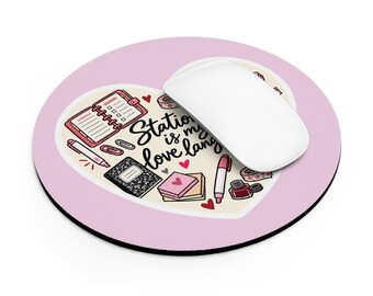 Op de afbeelding: Een ronde lichtroze muismat met een hartvormige illustratie met de tekst "Stationery is my love language". Het ontwerp bevat tekeningen van een planner, notitieboekjes, pennen, paperclips, plakbriefjes en een inktpot.