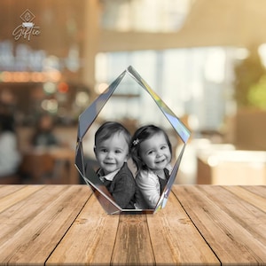 Op de afbeelding: Een kristallen, diamantvormige brievengewicht met een zwart-witfoto van twee kinderen erin. De kinderen lachen en kijken naar de camera.