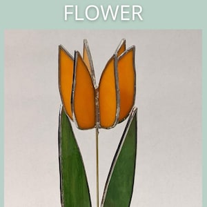 May include: A stained glass 3D tulip flower with orange petals and green leaves. The flower is mounted on a thin metal stem. The text "3D TULIP FLOWER" is at the top of the image, and "SAGE GLASSWORK" is at the bottom.