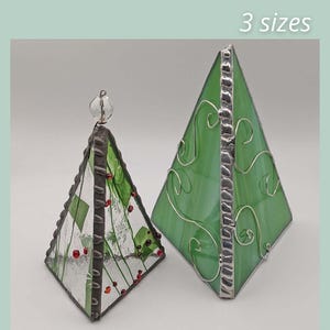 May include: Two decorative 3-sided Christmas tree ornaments. One is clear with green and red details, the other is green with silver wire. Text reads "3 SIDED CHRISTMAS TREE" and "3 sizes". The bottom text reads "SAGE GLASSWORK".