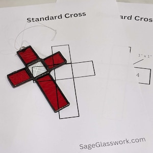 Puede incluir: Una cruz de vitral con piezas de vidrio rojo y blanco. La cruz mide 10 cm de ancho y 18 cm de alto. La cruz está sobre un fondo blanco con el texto "Standard Cross" y "SageGlasswork.com".