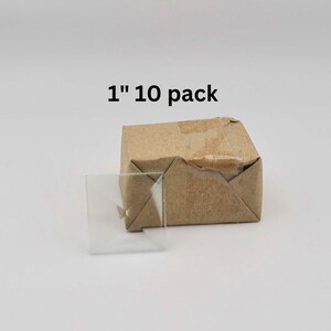 May include: A package of 10 clear glass squares, each measuring 1 inch, packaged in a brown paper box. The box is labeled "1" "10 pack".