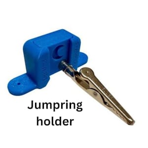 May include: A blue jumpring holder with a silver alligator clip. The holder has the text "Durist" on the side and the text "Jumpring holder" below the holder.