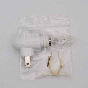 May include: A white plastic night light with a clear light bulb and a gold metal mounting bracket. The night light has a standard plug.