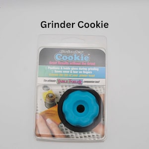 May include: A blue and black Grinder Cookie, a tool that positions and holds glass during grinding. The packaging features the text "Grinder Cookie" and "Great Results without the Grind".