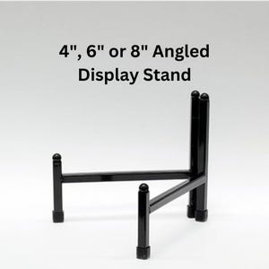 May include: Black metal angled display stand for objects. The stand is available in 4", 6", or 8" sizes.
