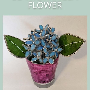 Op de afbeelding: Een 3D glaskunstwerk van een hortensia bloem in een roze pot. De bloem bestaat uit lichtblauwe glazen bloemblaadjes, met groene glazen bladeren aan weerszijden. De tekst "3D HYDRANGEA FLOWER" staat boven de bloem en "SAGE GLASSWORK" eronder.