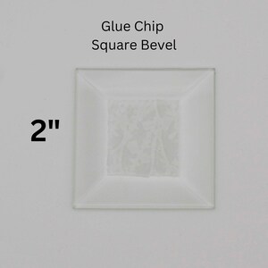 May include: A 2 inch square white glass tile with a beveled edge. The tile has a glue chip on the back for adhering to a surface. The tile is labeled "Glue Chip Square Bevel".