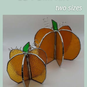 Könnte beinhalten: Zwei 3D-Glasmalerei-Kürbisse in Orange mit grünen Stielen und silbernen Drahtakzenten. Die Kürbisse gibt es in zwei Größen, und der Text "3D PUMPKIN" und "two sizes" sind sichtbar. Der untere Teil des Bildes lautet "SAGE GLASSWORK".