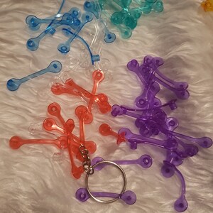 May include: Assortment of colourful plastic keychains in blue, purple, red, and clear. The keychains are shaped like a simple loop with two small circles on each end.