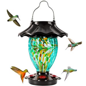 May include: A decorative hummingbird feeder with a black top and base, and a turquoise glass reservoir with colorful accents. Several hummingbirds are shown flying around the feeder. The feeder has a metal handle for hanging.