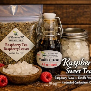 May include: A Raspberry Sweet Tea Kit featuring a clear pouch of raspberry tea leaves, a glass bottle of vanilla extract, a jar of rock sugar, and a wooden bowl filled with rock sugar, accompanied by fresh raspberries.