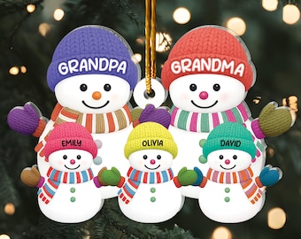 May include: A family of snowmen Christmas ornament. The ornament features a grandpa snowman with a purple hat, a grandma snowman with a red hat, and three smaller snowmen with personalized names. Each snowman wears a colorful scarf and mittens.