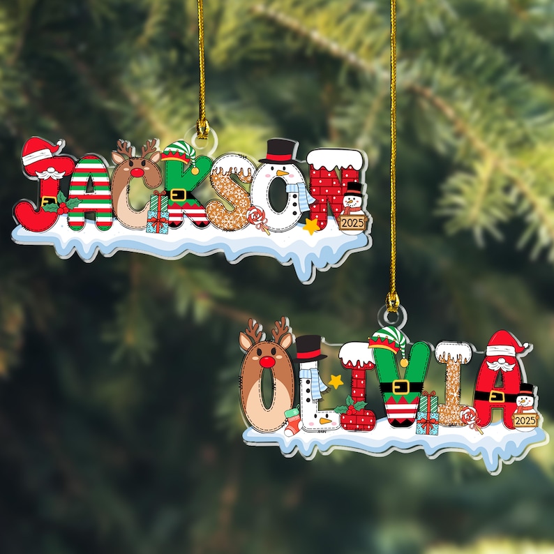 Puede incluir: Dos adornos navide&ntilde;os personalizados con los nombres JACKSON y OLIVIA en letras festivas. Cada letra incorpora personajes como Santa, renos, elfos y mu&ntilde;ecos de nieve, sobre una base nevada con cordones dorados para colgar.