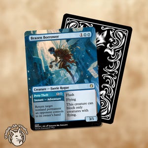May include: A Magic: The Gathering card featuring a blue and white illustration of a faerie rogue, titled "Brazen Borrower." The card has a black backing with a white decorative design. The card also has the text "Petty Theft" and "Flash."