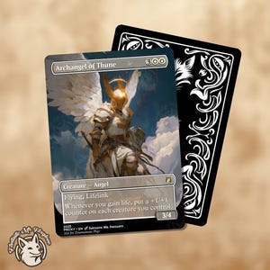 May include: A Magic: The Gathering card featuring "Archangel of Thune" with an angel illustration. The card has a white, gold, and blue color scheme, with text indicating creature type, abilities, and power/toughness. A black card with white decorative elements is behind it.