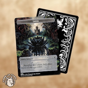 May include: A rectangular game card titled Lotus, featuring a dark lotus flower in a pond before a castle. The text reads Token Artifact and Sacrifice this token: Add three mana of any one colour. A second card with a black and white floral back is behind it.