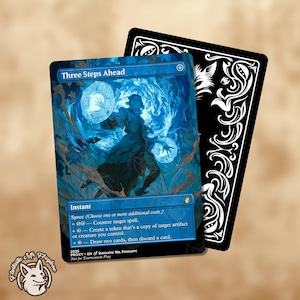 May include: A Magic: The Gathering card titled "Three Steps Ahead" with a blue and white illustration of a figure conjuring orbs of energy. The card is next to a black card with white decorative flourishes.