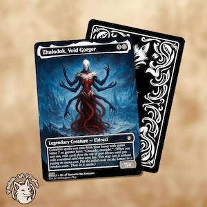 May include: A collectible card featuring the creature "Zhulodok, Void Gorger" with a blue and red color scheme. The card has a detailed illustration of a multi-armed creature. A black card with white decorative patterns is behind it.