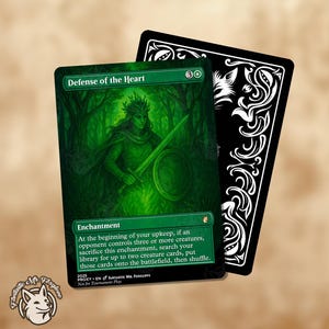 May include: A green "Defense of the Heart" card with a forest scene and a figure holding a sword and shield. The card has text describing its enchantment effect. A black card with white ornate designs is behind it. A circular logo with a fox is in the corner.