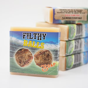 May include: A stack of four bars of soap with a baseball theme. The front bar has a blue background with two baseballs and the text "FILTHY BALLS SOAP".