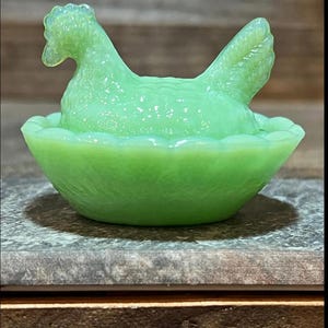 K&ouml;nnte beinhalten: Eine gr&uuml;ne Glasschale in Form eines Huhns mit einem Nest. Die Schale ist aus Depressionsglas und ein Vintage-Artikel.
