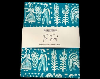 Könnte beinhalten: Ein gefaltetes türkisfarbenes Geschirrtuch mit einem weißen Volkskunstdesign mit Figuren, Pflanzen und geometrischen Formen. Das Handtuch ist mit "Tea Towel" beschriftet und misst 50 x 70 cm. Hergestellt aus 100 % Baumwollköper.