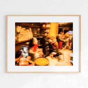 Puede incluir: Una imagen borrosa de un grupo de personas en una habitación con poca luz. Las personas están de pie alrededor de una mesa, y algunas sostienen bebidas. La habitación está decorada con luces de cadena y otras decoraciones festivas.