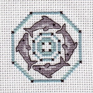 May include: A cross-stitch pattern featuring six gray dolphins arranged in a circle around a blue and white geometric design.