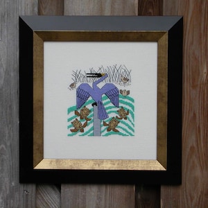 May include: Cross-stitch artwork of a blue bird with spread wings, perched on a post, surrounded by turtles and birds. The artwork is framed in a black frame with a gold inner edge, set against a wooden background.
