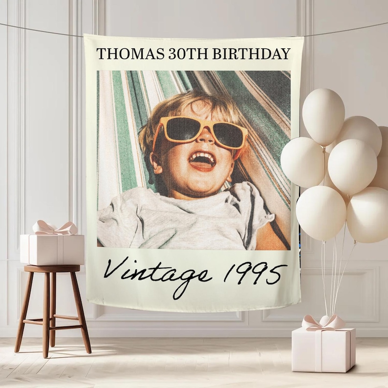 May include: A personalized photo banner with the text "THOMAS 30TH BIRTHDAY" at the top and "Vintage 1995" at the bottom. The banner features a photo of a child wearing sunglasses. White balloons and a gift box are also present.