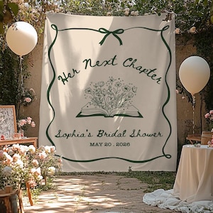 May include: A cream-colored banner with dark green lettering and a decorative border. The text reads "Her Next Chapter" above an illustration of an open book with flowers. Below, it says "Sophia's Bridal Shower" and the date "MAY 20. 2026".