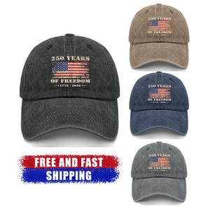 May include: Baseball caps in various colors, including black, brown, and blue, each featuring the text "250 YEARS OF FREEDOM" and an American flag design. The caps are made of a textured fabric and have a curved brim.