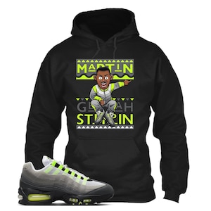 Puede incluir: Sudadera con capucha negra con un gr&aacute;fico de dibujos animados de un hombre se&ntilde;alando, con el texto "MARTIN" y "GEEAH STARIN" en verde ne&oacute;n y blanco. Un par de zapatillas grises, negras y verde ne&oacute;n est&aacute;n en primer plano.