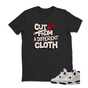 May include: Black t-shirt with the text "CUT FROM A DIFFERENT CLOTH" in white and red, featuring scissors. A pair of white and black sneakers with red accents are at the bottom of the image.