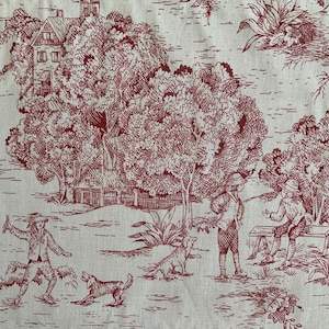 Puede incluir: Una tela de color crema con un patr&oacute;n toile repetitivo en tinta roja oscura. El dise&ntilde;o representa una escena pastoral con casas, &aacute;rboles grandes y figuras de personas interactuando con perros en un entorno natural.