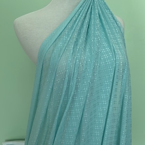 May include: A light blue fabric with a white geometric pattern. The fabric is draped over a white mannequin.