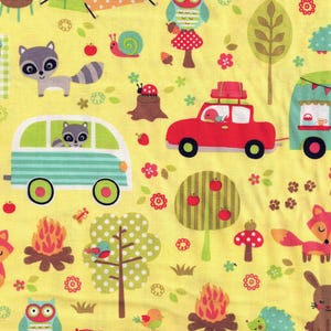 May include: Yellow fabric with a camping theme. Features illustrations of a tent, owls, raccoons, a red car, a camper, trees, a campfire, and woodland creatures. Includes the text "INCHES" and "Cindy Chock's Sewing Room".