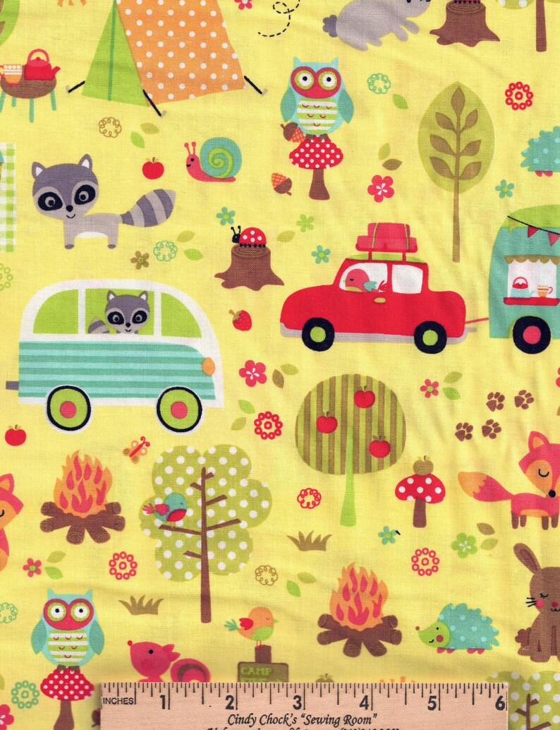 May include: Yellow fabric with a camping theme. Features illustrations of a tent, owls, raccoons, a red car, a camper, trees, a campfire, and woodland creatures. Includes the text "INCHES" and "Cindy Chock's Sewing Room".