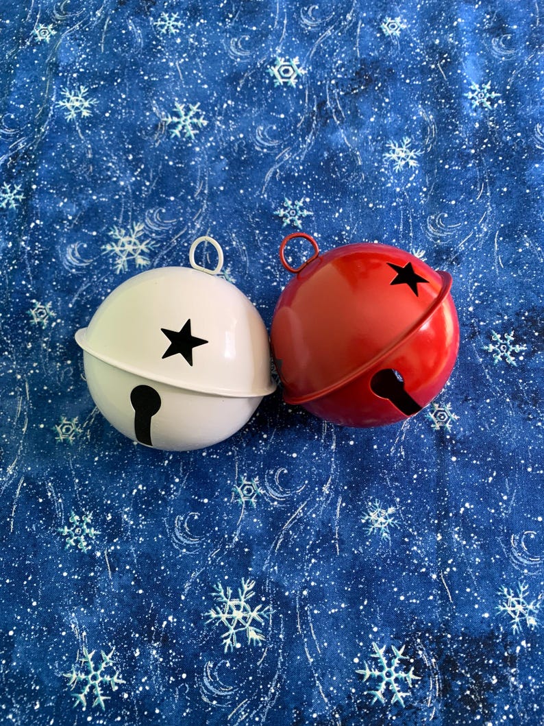 Puede incluir: Dos cascabeles esf&eacute;ricos de metal, uno blanco y otro rojo, cada uno con un recorte en forma de estrella en la parte superior y una abertura vertical en forma de cerradura en la parte inferior, con una peque&ntilde;a anilla met&aacute;lica para colgar.