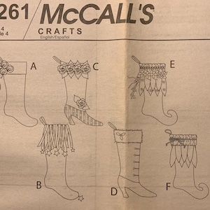 May include: McCall's M5261 Crafts sewing pattern sheet featuring line drawings of six different Christmas stocking designs labeled A through F. The illustrations show various decorative elements including bows, flowers, fringe, stars, and cuffs on different stocking shapes.