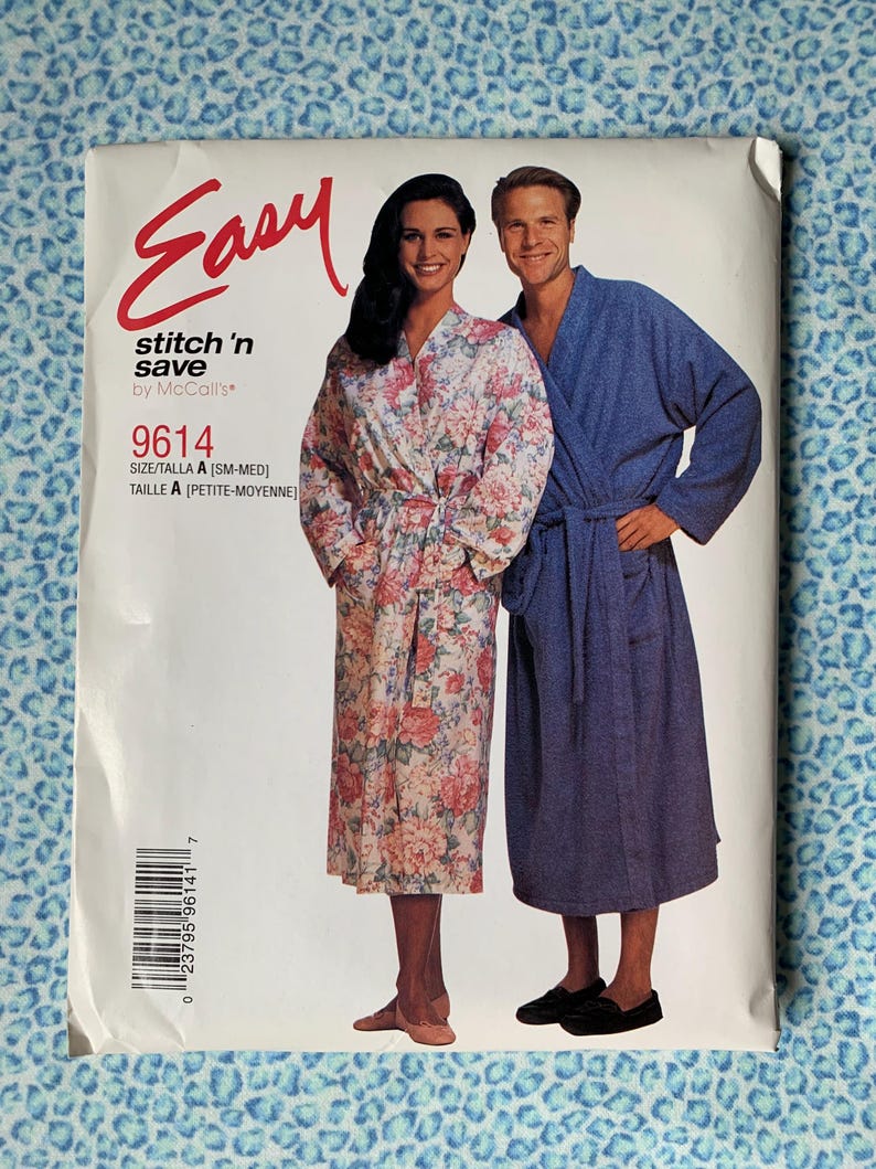 May include: A McCall's Easy stitch 'n save sewing pattern envelope 9614 for robes. The front shows two people wearing robes: one in a white floral print and one in solid blue. The text includes Easy, stitch 'n save, 9614, and size A [SM-MED].